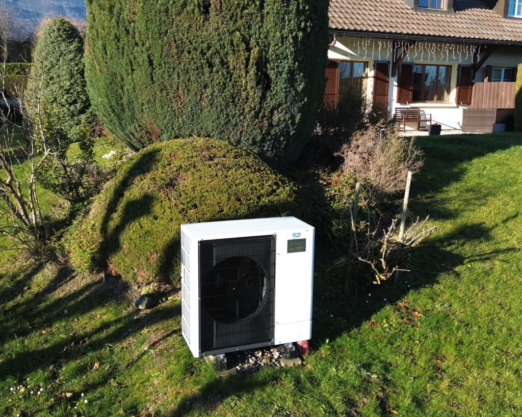 Image d'une jardin avec une pompe à chaleur blanche Mitsubishi posé par l'entreprise suisse AFM