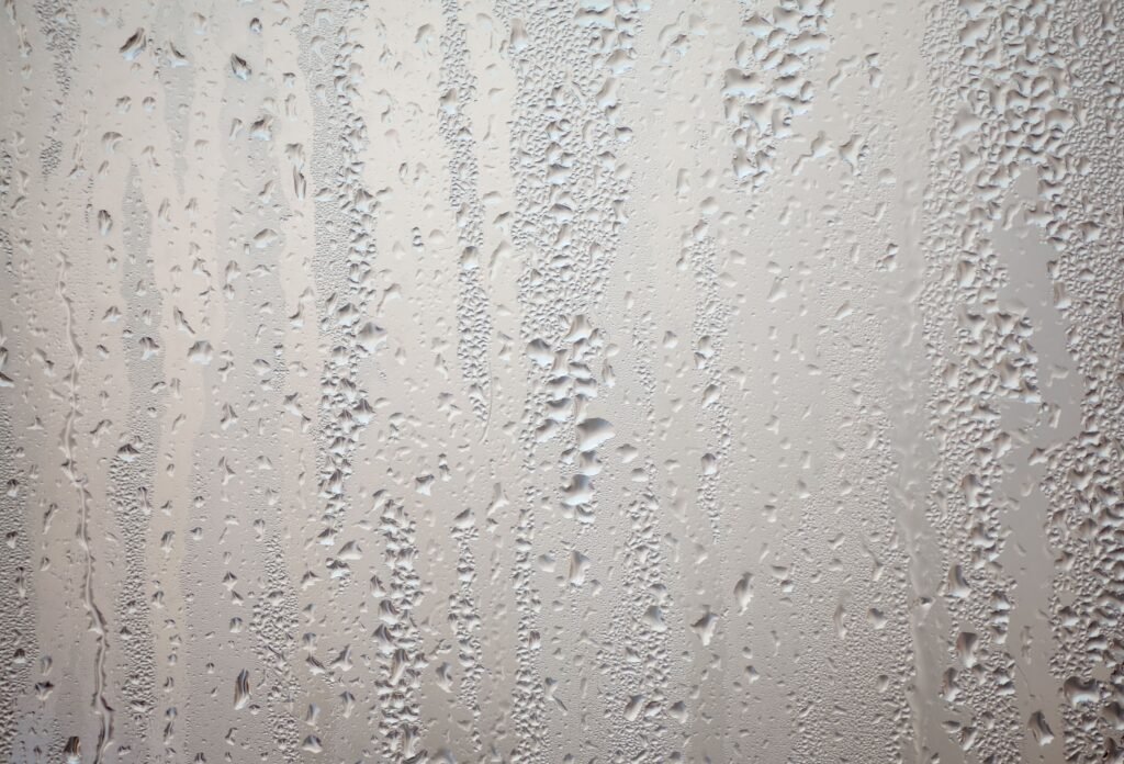 Detailed view of water droplets creating patterns on glass surface.